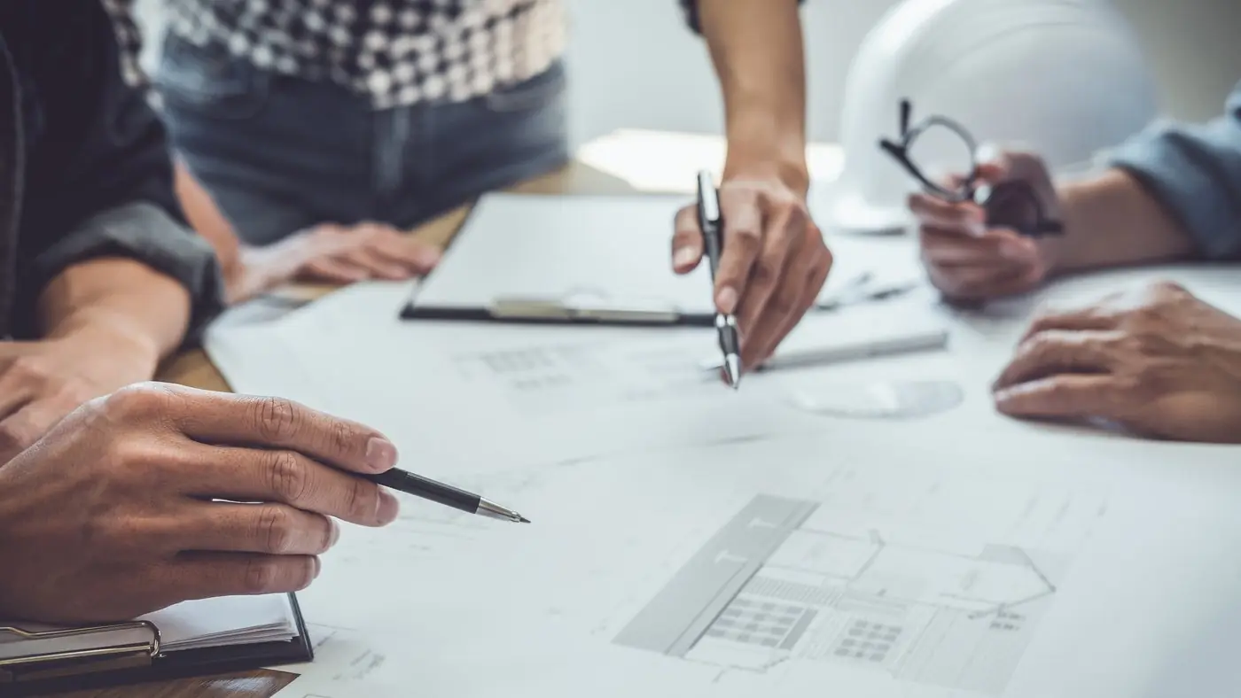 Two people working through a plan on paper with pens